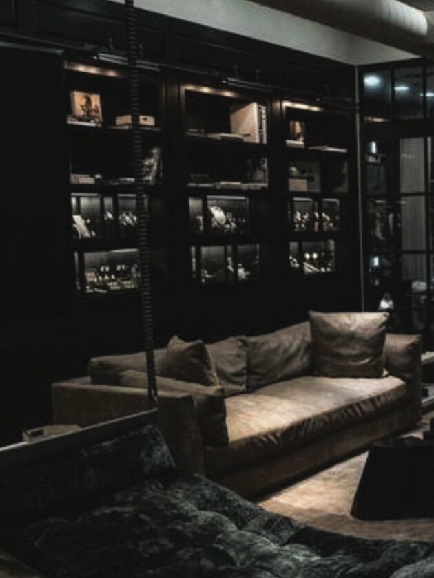 A lit shelving wall above a sofa in a dark lounge, standing in for an unannounced show.