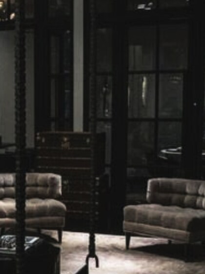 Armchairs beside a glazed partition in a dark lounge.