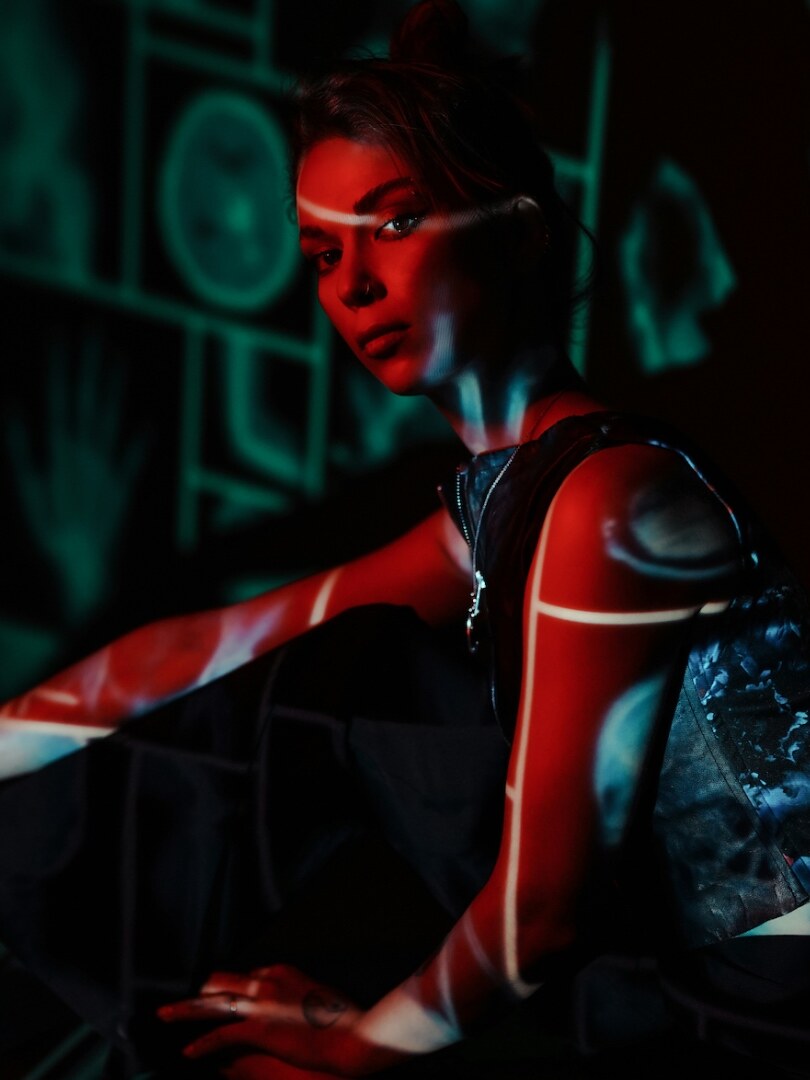 Editorial portrait with projected red and teal light used as category placeholder.